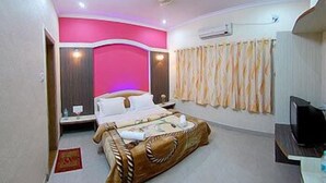 A bedroom with a bed, a television, and a curtain. - Shanti's Hotel Sonai (Mahabaleshwar)