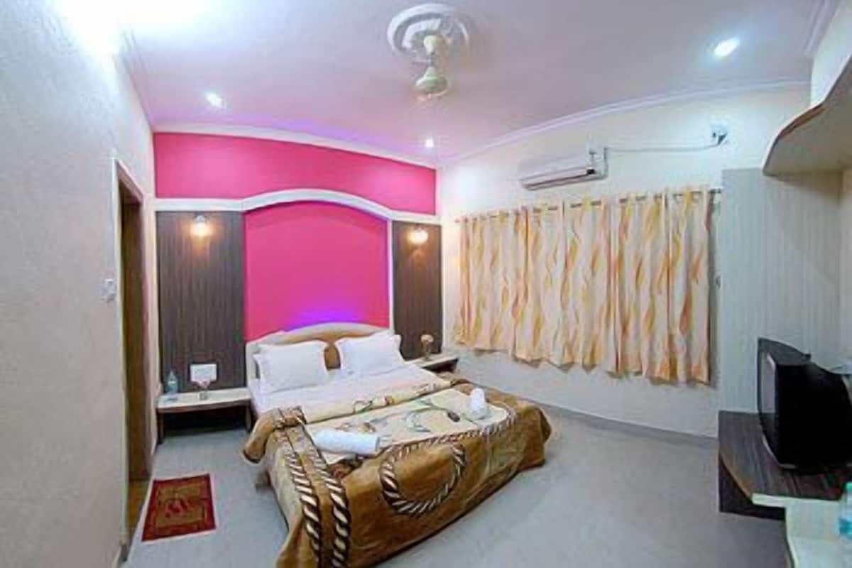 A bedroom with a bed, a television, and a curtain.