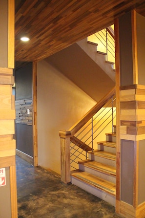 A wooden staircase with a metal railing, leading to an upper floor.