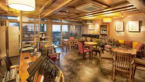 Un café acogedor con mobiliario de madera, una zona de bar y vistas a través de amplios ventanales.