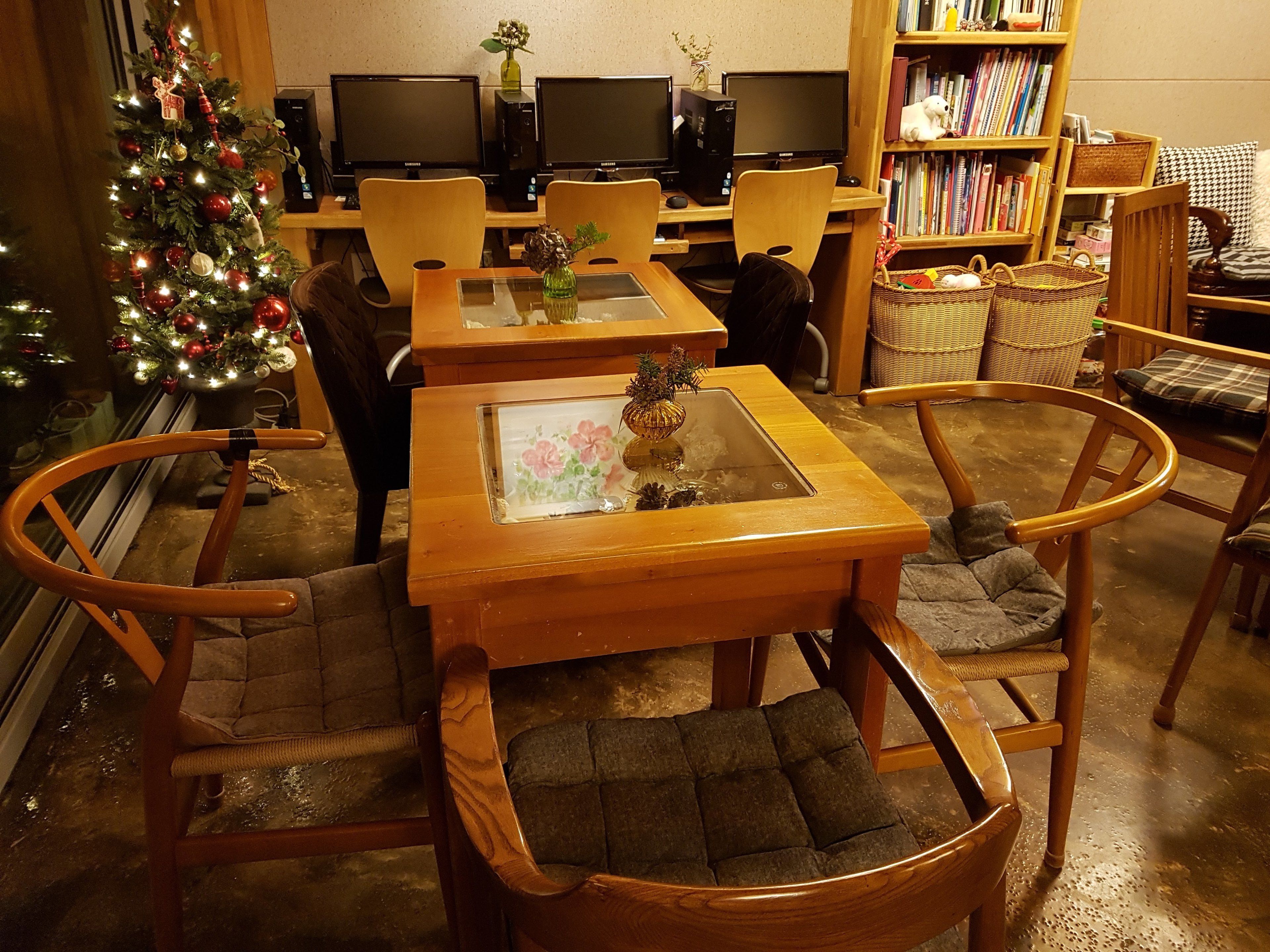 Una sala de estar acogedora con una mesa de centro de madera, sillones cómodos, un árbol de Navidad y una estantería llena de libros y adornos.