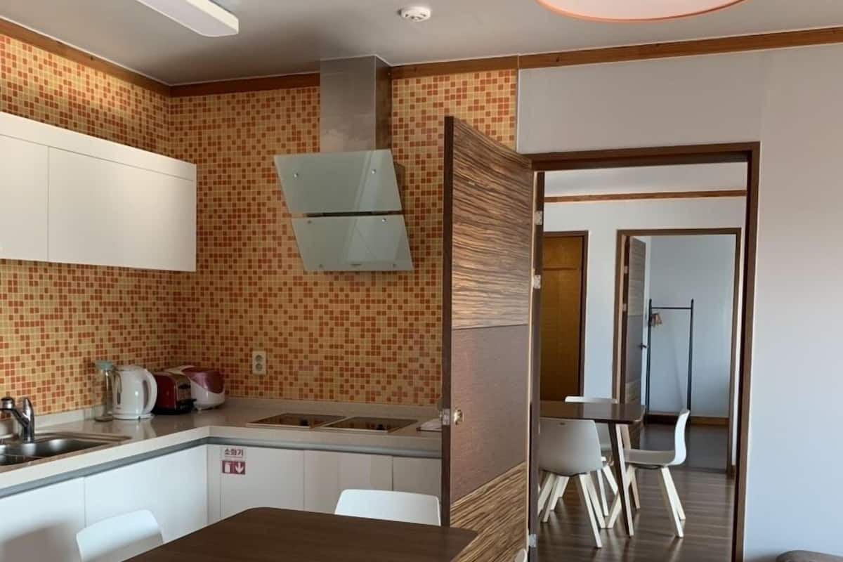 Uma cozinha moderna com armários brancos, uma mesa de jantar de madeira e cadeiras brancas.