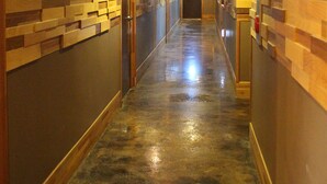 Un pasillo largo y estrecho con paneles de madera en las paredes y suelo de concreto pulido.