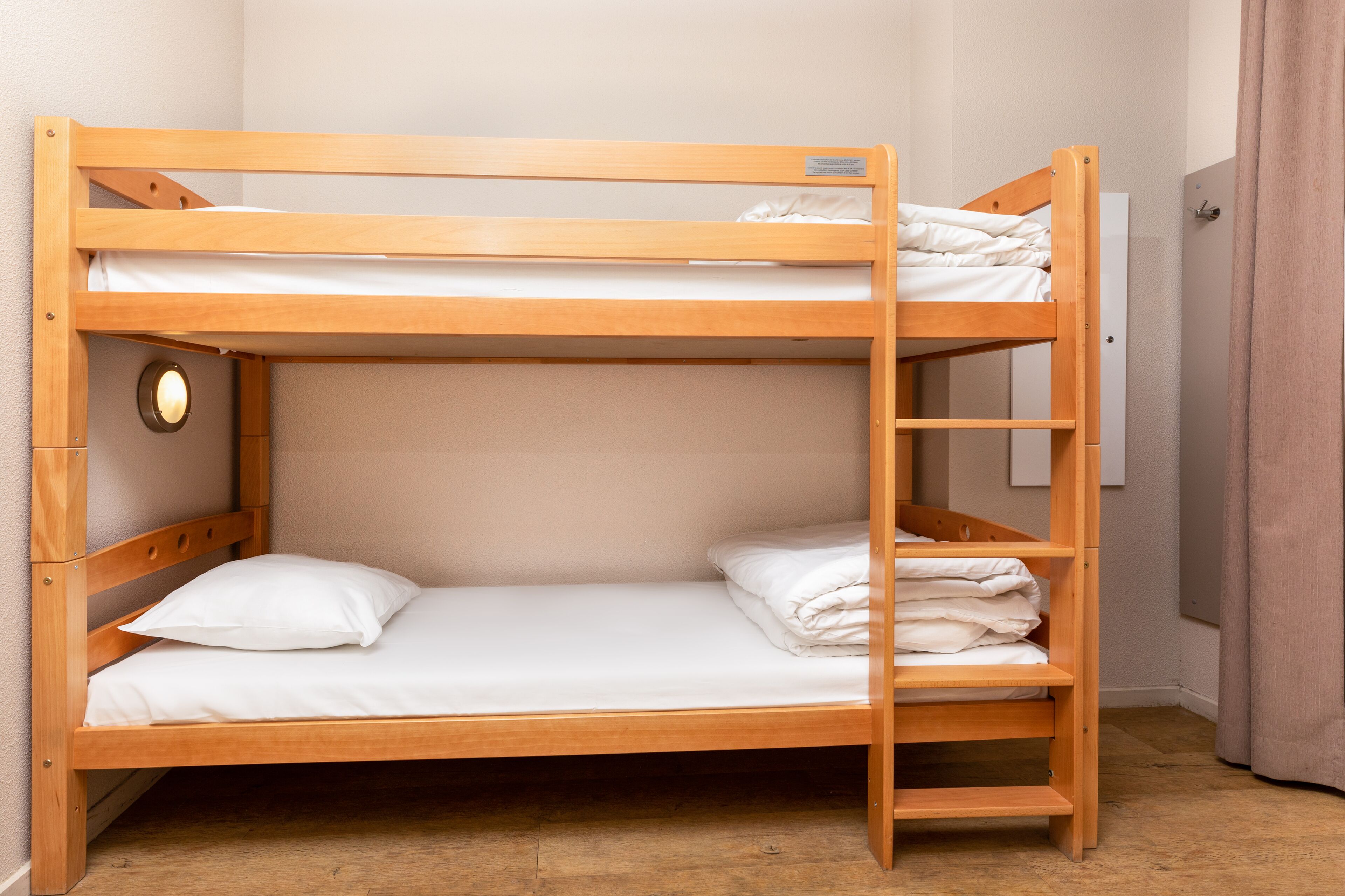 Een stapelbed met houten frame, twee kussens en een klein plankje.
