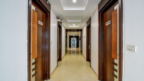 Un pasillo de hotel con puertas de madera, suelo de baldosas e iluminación empotrada en el techo.