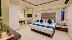 Una habitación de hotel moderna con una cama grande, un escritorio con silla, televisión y ventilador de techo.