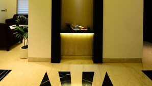 A lobby with a reception desk, a plant, and a modern ceiling design. - Hotel City Star (New Delhi)