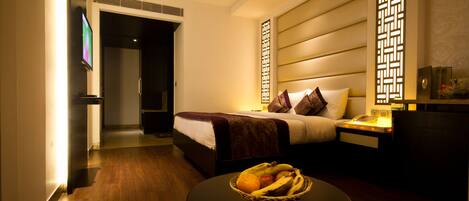 A hotel room with a bed, bedside table, and a fruit basket.