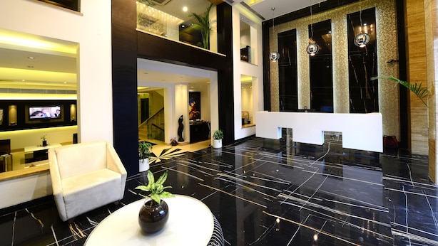 A modern lobby with a reception desk, seating area, and a large mirror reflecting the space. - Hotel City Star (New Delhi)