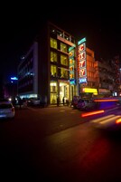 Een hotel met een opvallend neonbord, meerdere verdiepingen en een zichtbare ingang.