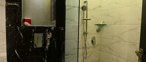 A bathroom with a toilet, a shower, and a glass-enclosed shower area.
