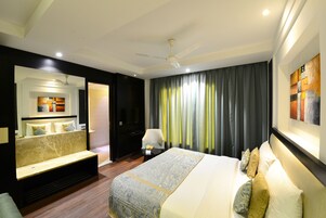 Une chambre d’hôtel comprenant un lit, un coin salon, un bureau et un ventilateur de plafond.