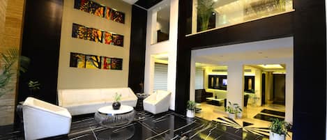 A modern lobby with a black marble floor, white sofas, and a central round table.