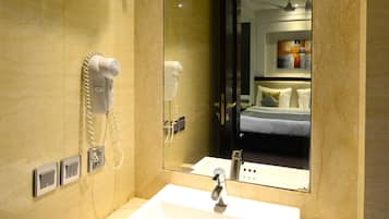 A hotel bathroom with a large mirror, a sink, a hairdryer, and a towel rack.