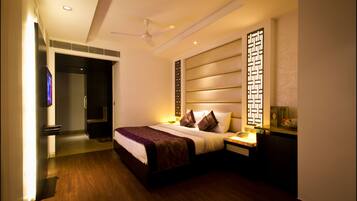 A modern hotel room with a large bed, bedside tables, a ceiling fan, and a decorative screen.