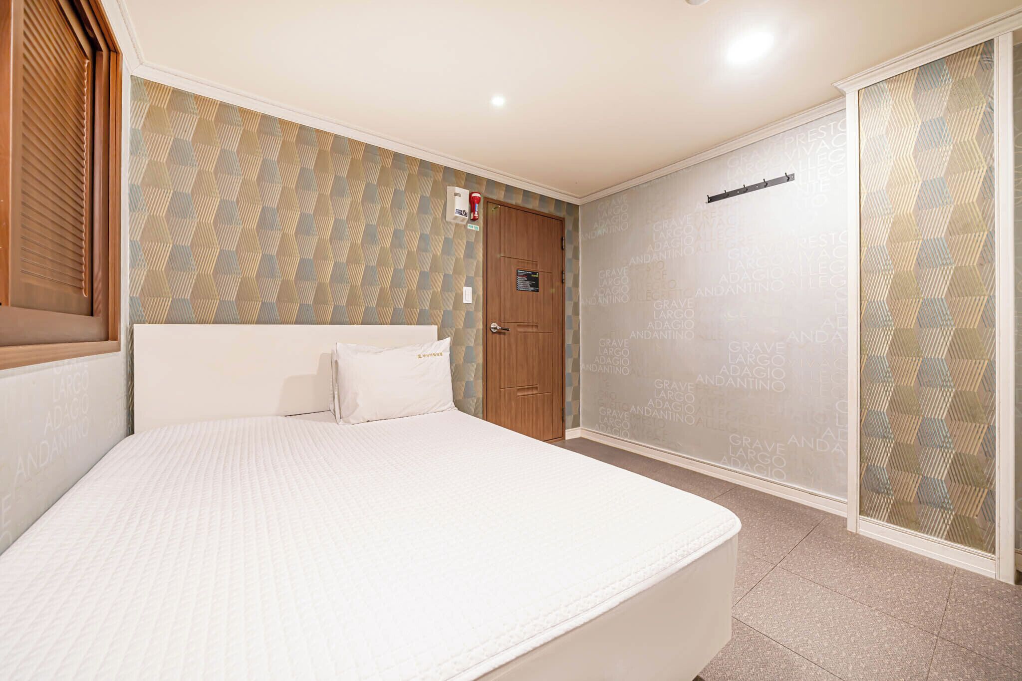 Una camera da letto con un letto, una porta in legno e carta da parati decorata.