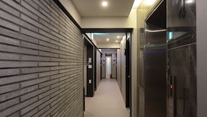 Un couloir moderne, avec un mur en briques d’un côté et les portes d’ascenseur de l’autre.