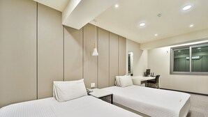Une chambre d’hôtel avec deux lits, un bureau, une chaise, un miroir et une fenêtre.