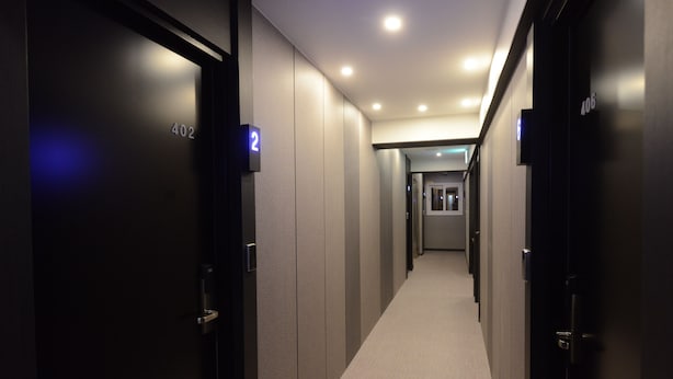 Un couloir avec des portes numérotées 402 et 2, menant à une pièce dont la porte est marquée du numéro 406.