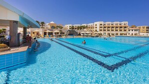 A large swimming pool with clear blue water, surrounded by lounge chairs and umbrellas. - Old Palace Resort Sahl Hasheesh (Sahl Hasheeh)