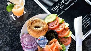 Ein Teller mit einem Bagel, Räucherlachs, Gemüse und einem Getränk, zusammen mit einer Speisekarte und einem Servietttuch.