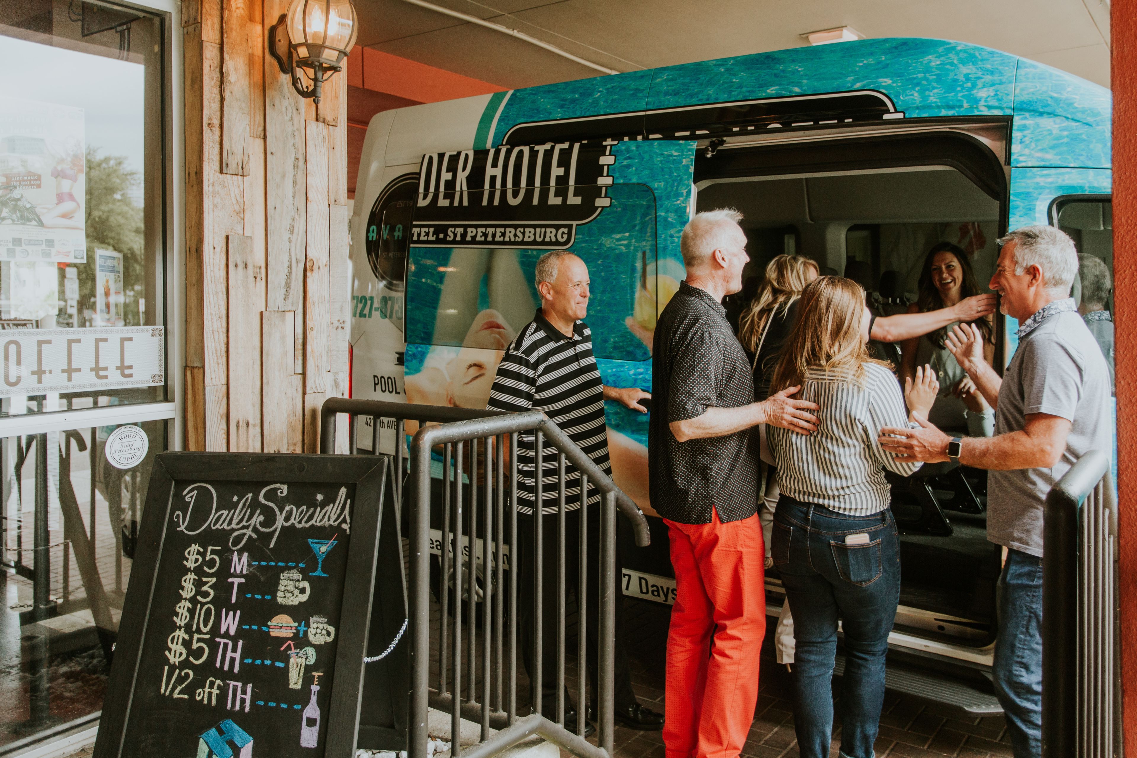 Un camion-restaurant, avec une enseigne indiquant « DER HOTEL » et « TÉL. – SAINT-PÉTERSBOURG », est stationné devant un immeuble.
