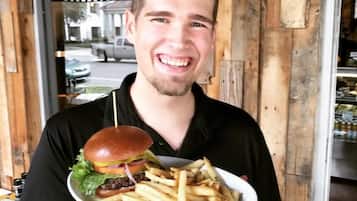 Una persona sosteniendo un plato con una hamburguesa y papas fritas.