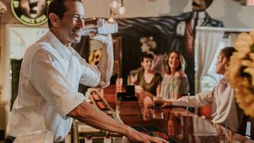 Een barman schenkt een drankje in een bar met een retro inrichting, inclusief een muurschildering en kaarsen.