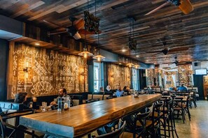 A restaurant with wooden ceiling and walls, hanging pendant lights, and a long wooden bar. - Hollander Boutique Hotel (St. Petersburg)