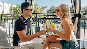 A couple toasting with champagne glasses on a balcony with a pool view. - Hollander Boutique Hotel (St. Petersburg)