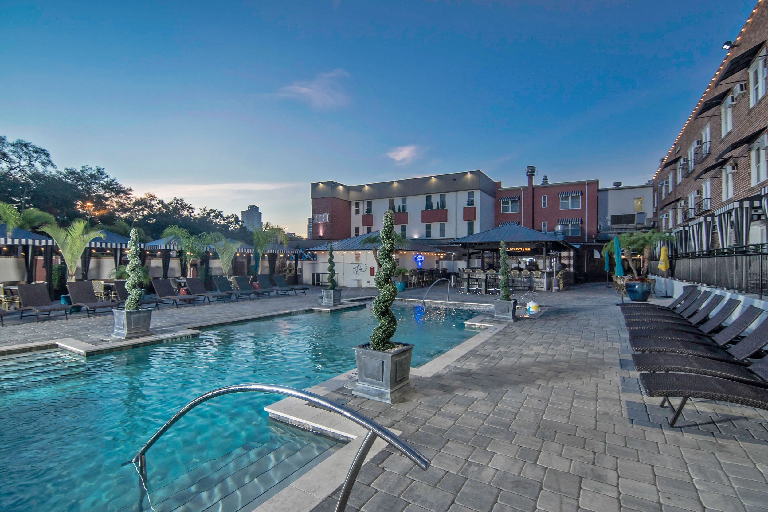A hotel pool area with lounge chairs and a bar.