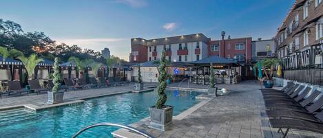 A hotel pool area with lounge chairs and a bar.