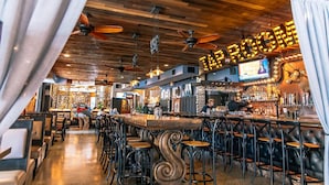 A bar area with wooden ceiling, bar stools, and a counter with a TV screen. - Hollander Boutique Hotel (St. Petersburg)