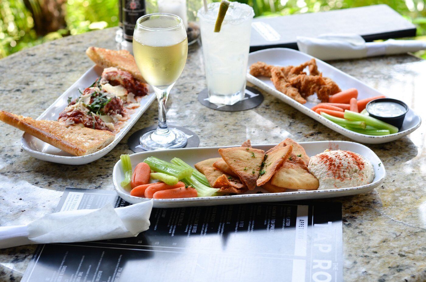 A meal with bread, vegetables, and a drink on a table with a menu.