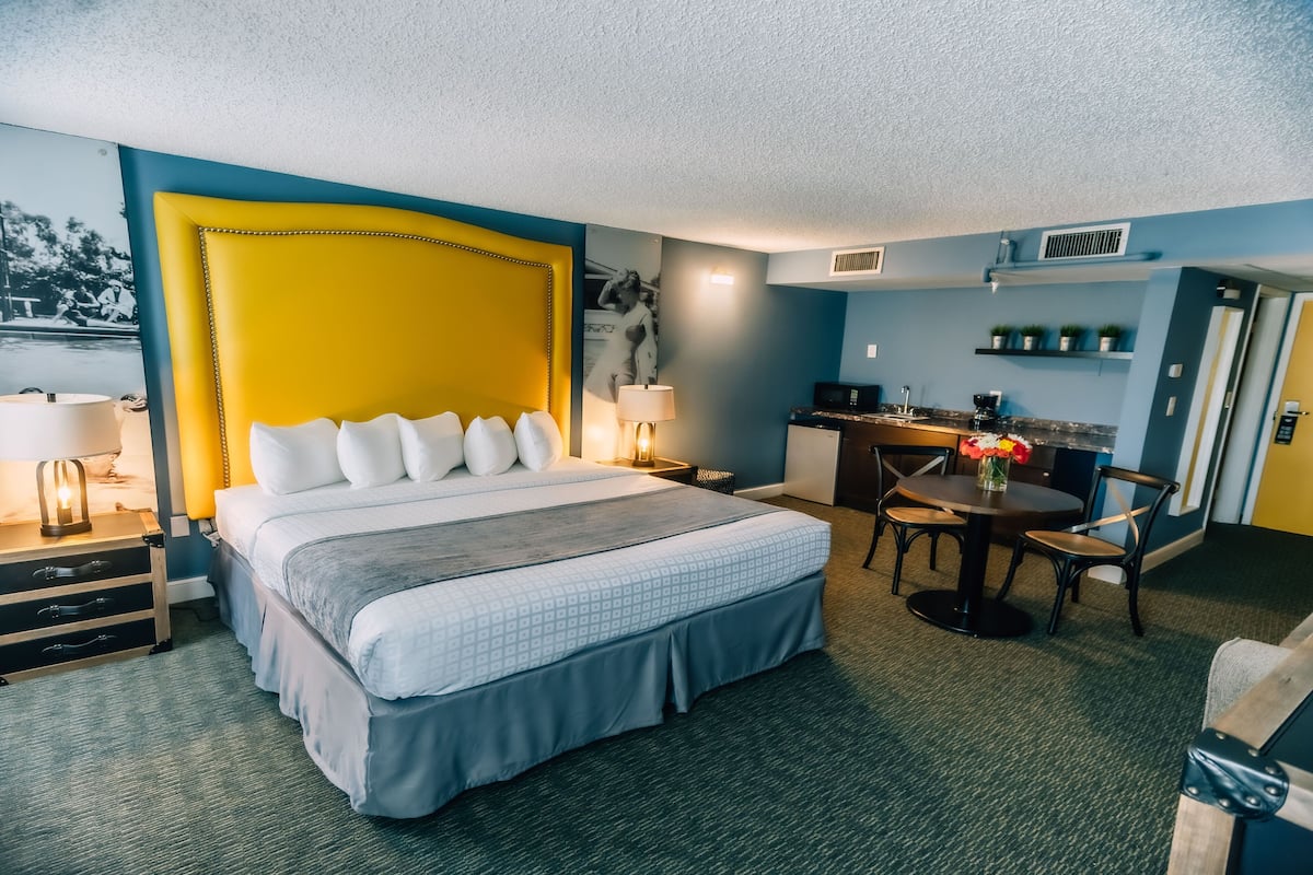 A hotel room with a large bed, a desk, and a chair.