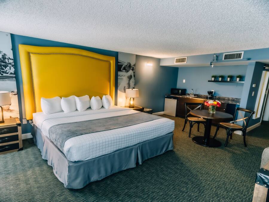 A hotel room with a large bed, a desk, and a chair.