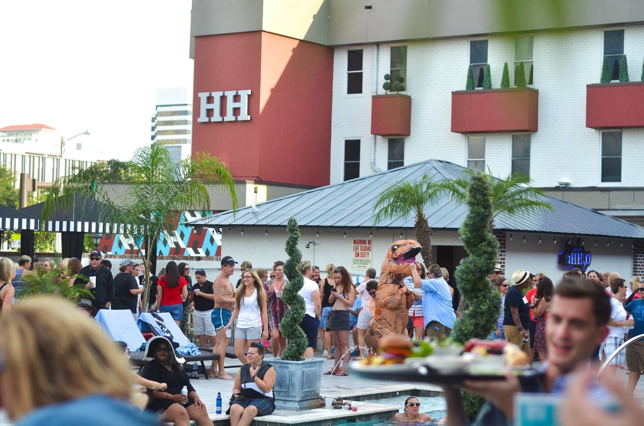 Un hôtel reconnaissable à son grand panneau « HH », doté d’une piscine extérieure avec des chaises longues et surveillé par un maître-nageur.