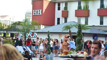 Un hôtel reconnaissable à son grand panneau « HH », doté d’une piscine extérieure avec des chaises longues et surveillé par un maître-nageur.