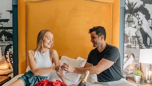 A couple sitting on a bed with a bottle of champagne and a bouquet of red roses. - Hollander Boutique Hotel (St. Petersburg)