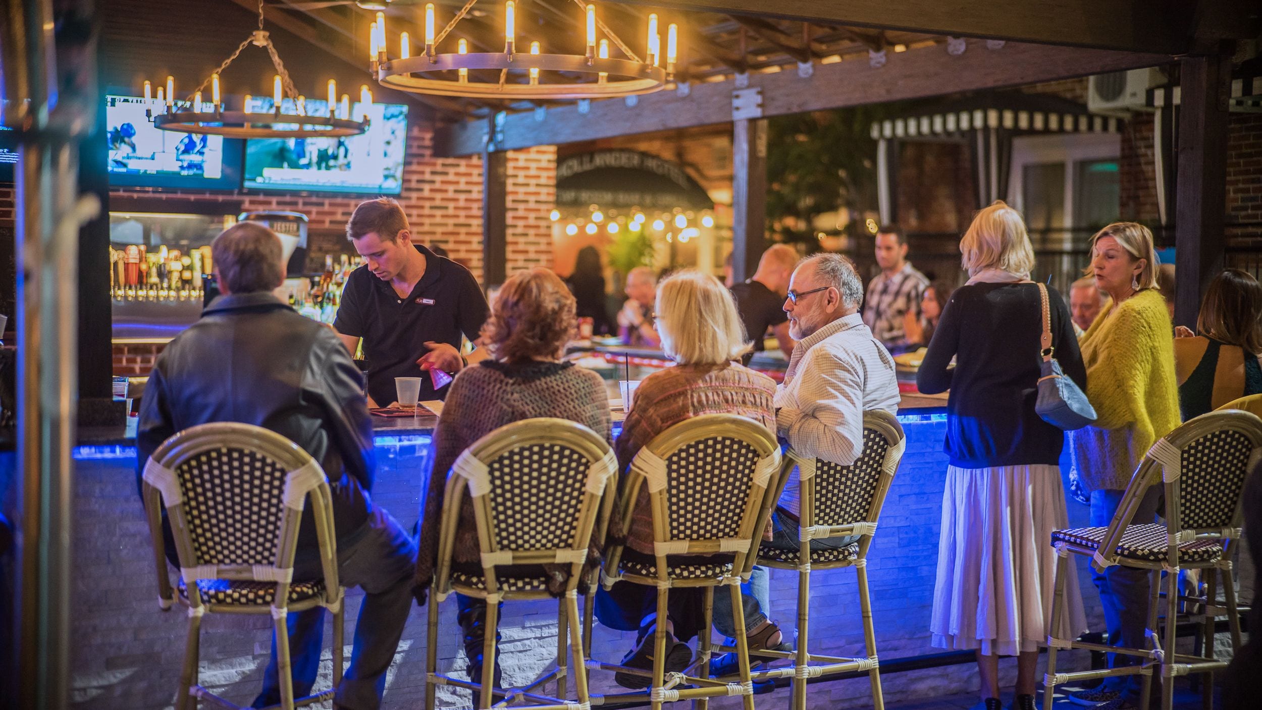 A bar area with wicker chairs, a bartender, and patrons.