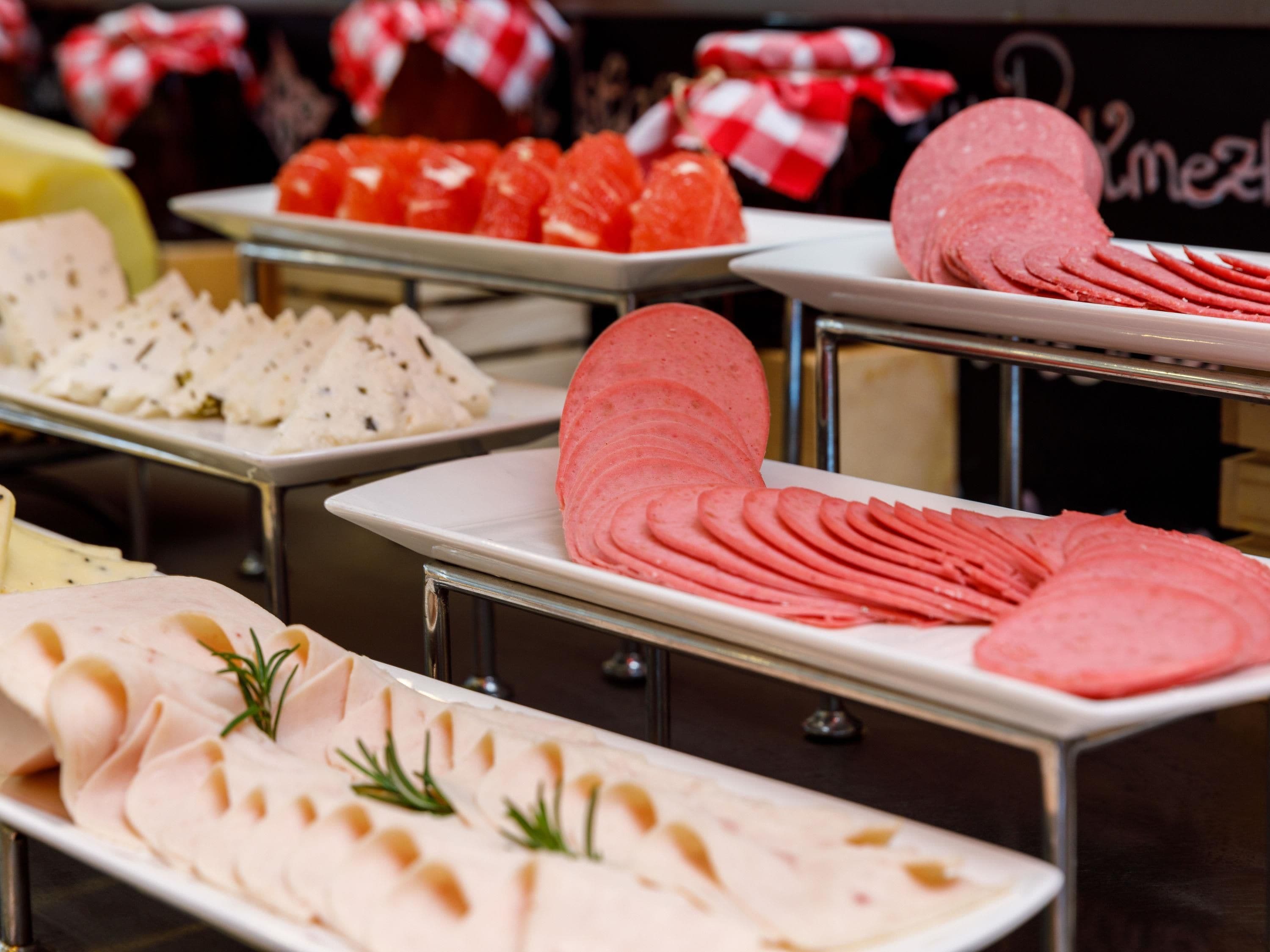A buffet with various food items including sliced meats and fruits.