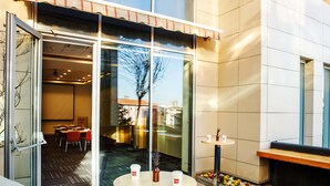 A modern hotel lobby with a glass door entrance, a small round table with two cups, and a bench. - ibis Istanbul Esenyurt (Istanbul)