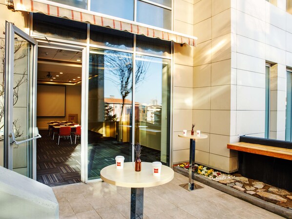 A modern hotel lobby with a glass door entrance, a small round table with two cups, and a bench. - ibis Istanbul Esenyurt (Istanbul)