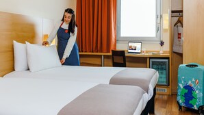 A hotel room with two beds, a desk with a computer, a mini-fridge, and a suitcase. - ibis Istanbul Esenyurt (Istanbul)