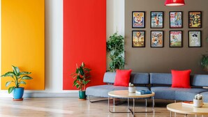 A modern living room with a grey sofa, red cushions, a round coffee table, and a large red accent wall. - ibis Istanbul Esenyurt (Istanbul)