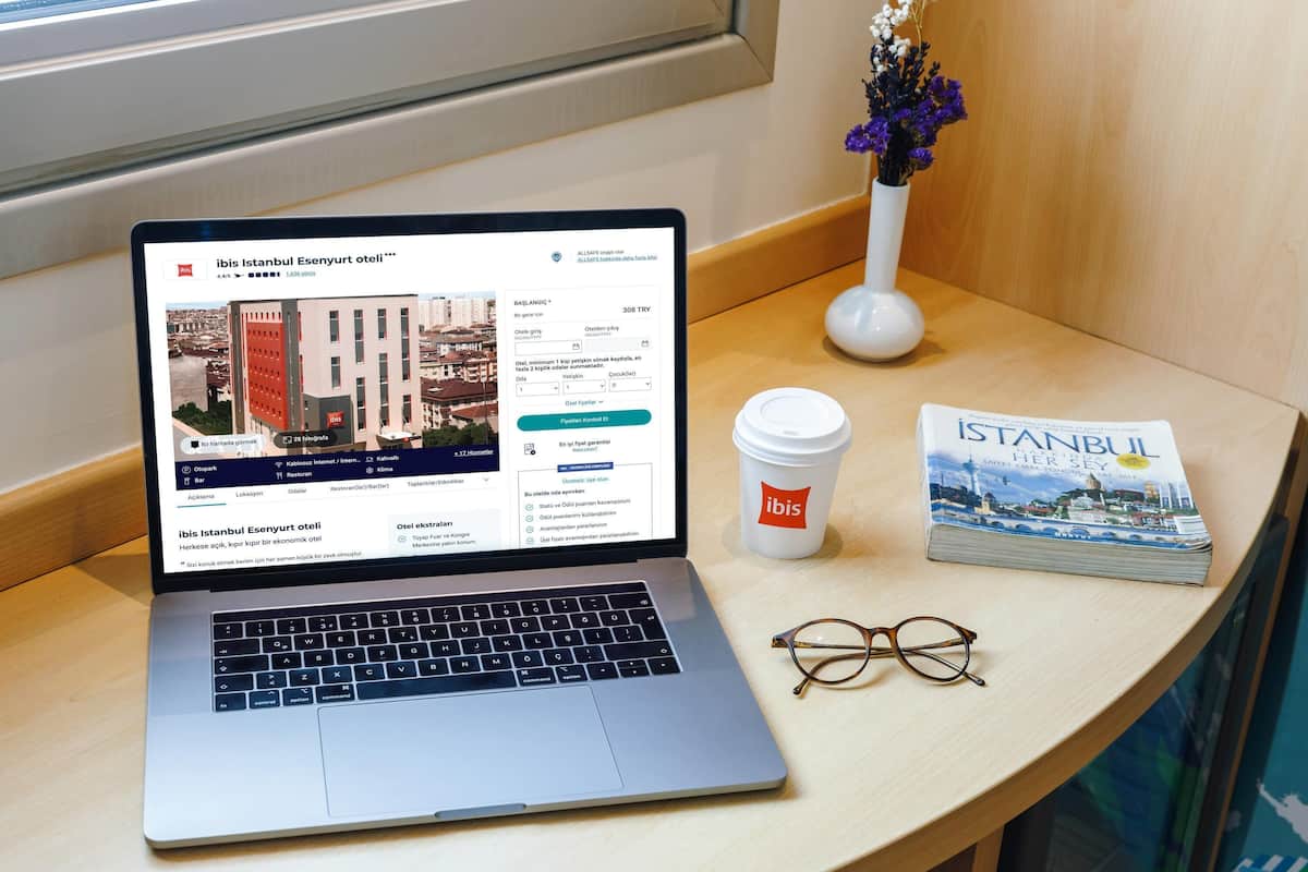 A laptop on a table with a book and a coffee cup beside it.
