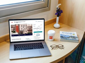 A laptop on a table with a book and a coffee cup beside it. - ibis Istanbul Esenyurt (Istanbul)
