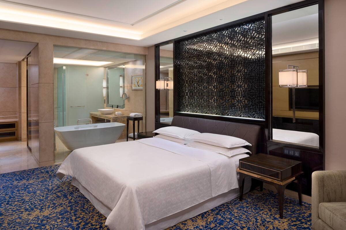 Een hotelkamer met een groot bed, een badkamer met een bad, een bureau en een stoel.