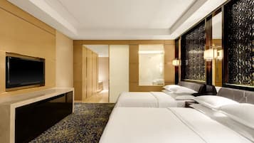 A hotel room with two beds, a flat-screen TV, a desk, and a decorative wall panel.