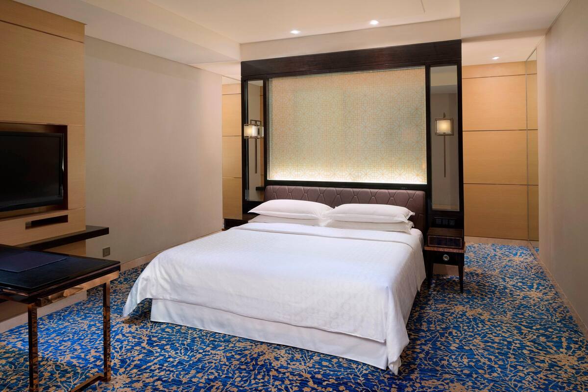 Een hotelkamer met een groot bed, een flatscreen televisie, een nachtkastje en een decoratief paneel aan de muur.